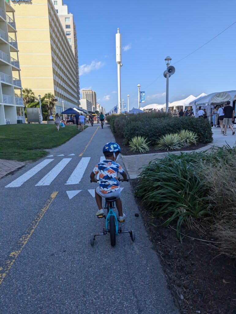 Child riding bike on beach boardwalk